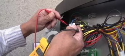 Hands working an an outdoor AC unit