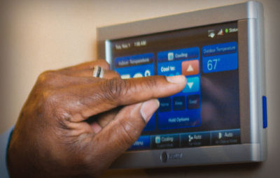 A hand programming a digital thermostat