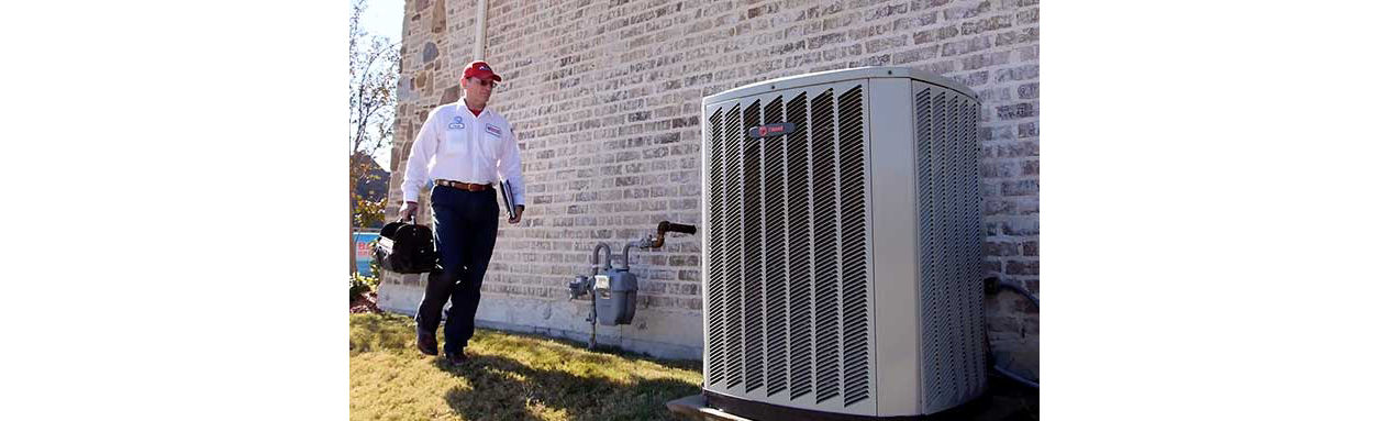 Technician walking up to AC unit with toolbag