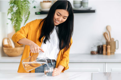 woman pouring herself a glass of fresh water in her home