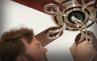 An electrician working on a ceiling fan