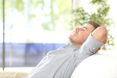 A man relaxing in a comfy chair on a screened in porch