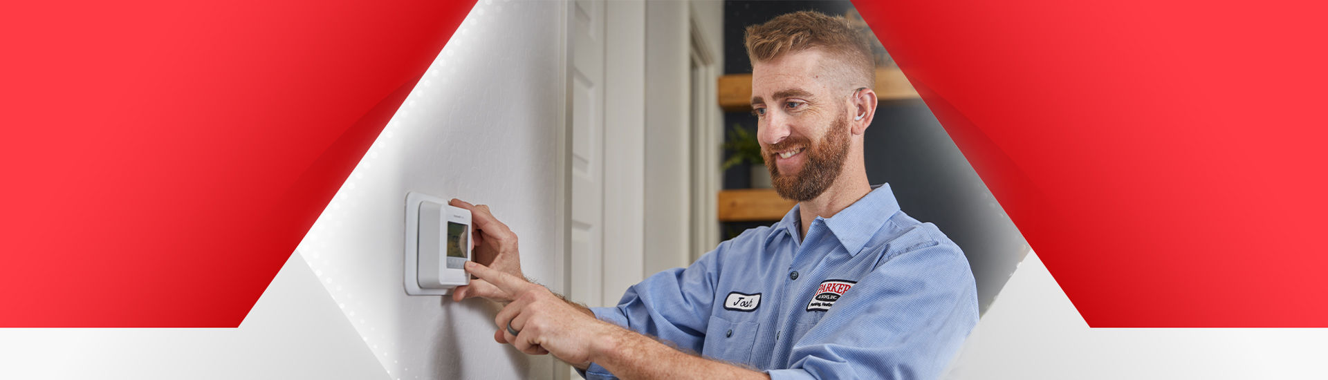 Parker & Sons Heating technician looking at thermostat smiling