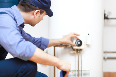 service tech inspecting a tank water heater for customer