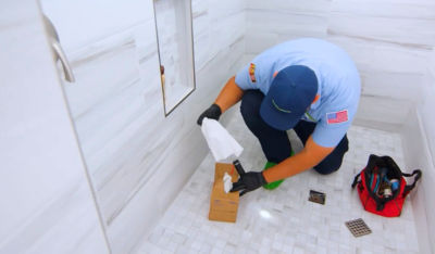 Technician fixing a drain in a shower.