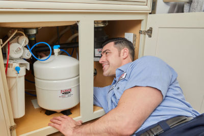 water tech adjusting an RO water system under the sink