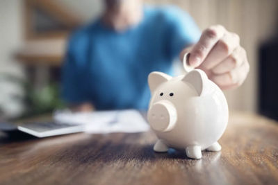 A man putting a coin in a piggy bank.