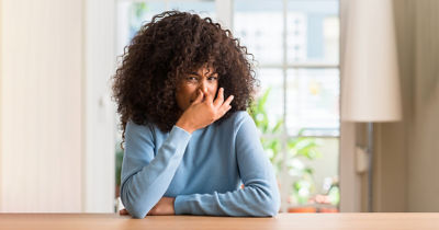 Woman holding her nose due to bad smell