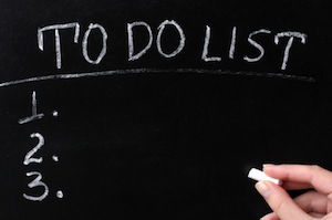 Hand with chalk writing to do list on chalkboard