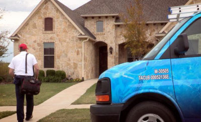 Plumber walking up to  house with toolbag