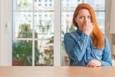 woman in home plugging her nose due to bad smell