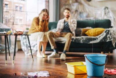 couple sitting on couch calling a plumber because they have a home water leak